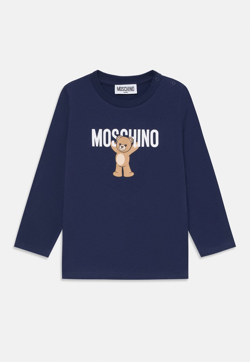 Tumši zila garām piedurknēm t-krekls, izgatavots no mīksta kokvilnas materiāla, ar brūnā lāča grafiku un "MOSCHINO" tekstu. Viegli uzvelkamais aizdare plecā.