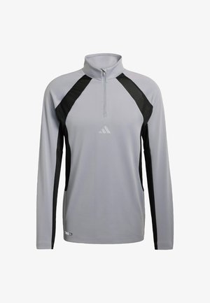 Jasnoszara, długorękawowa koszulka sportowa z czarnymi panelami bocznymi, zamkiem do ćwierć wysokości i małym logo Adidas na klatce piersiowej.