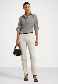 Mustavalkoraidallinen napillinen paita, valkoiset kireät farkut, musta vyö, pieni musta käsilaukku ja mustat korkokengät.