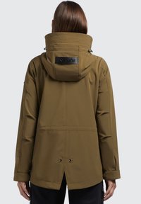 Giacca impermeabile verde oliva con alto colletto, cappuccio regolabile e patch nero del logo. Presenta ventole laterali e un design a vestibilità rilassata.