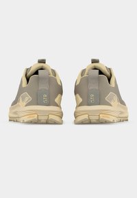 Ζευγάρι πεζοπορικών παπουτσιών σε μπεζ και γκρι χρώμα, εμφανιζόμενα από πίσω, με θηλιές έλξης που φέρουν την ετικέτα "GTR" και υφή σόλας, σε λευκό φόντο.