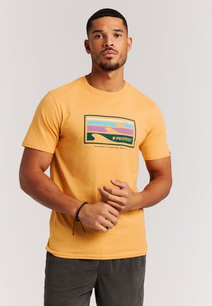 Geel katoenen T-shirt met een grafisch ontwerp van golven in paars, blauw en groen. Korte mouwen en een ronde hals.