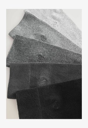 Zobrazených je päť párov ponožiek, rôzne odtiene od svetlošedej po čiernu. Textúrovaná tkanina s rebrovanými manžetami a jemným detailom loga.