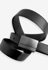 Czarny pasek ze skóry o gładkim wykończeniu oraz teksturowaną metaliczną klamrą w kształcie płaskiego prostokąta. Regulowana długość z dziurkami.