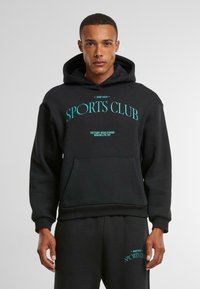 Svart hettegenser med frontlomme, med turkise bokstaver: "ANOTHER SPORTS CLUB" og "VICTORY BOULEVARD, BROOKLYN, NY."