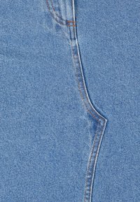 Tela de mezclilla azul clara con un diseño de costura distintivo y un contraste de hilo naranja. Textura suave con áreas sutilmente desgastadas.