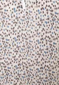 Tissu crème avec une texture plissée présentant un motif de petits motifs floraux bleus et marron avec de fines branches marron.