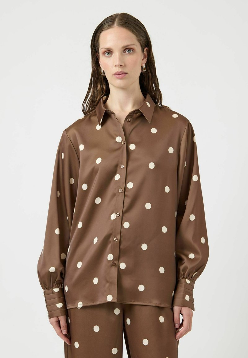 Blusa in raso marrone con grandi pois crema, chiusura con bottoni sul davanti, colletto appuntito e polsini con bottoni e texture arricciata.