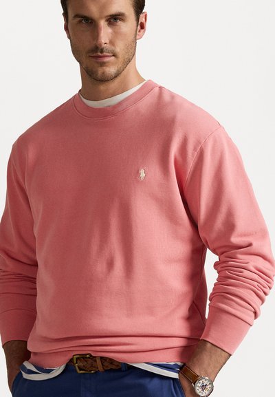 Rózsaszín crewneck pulóver puha anyagból, hosszú ujjal, hímzett logóval a mellrészen. Kényelmes szabás, bordázott részletekkel.