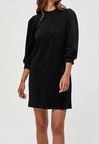 Robe noire à manches courtes en tissu doux, avec des manches bouffantes et un col rond. Texture lisse avec une coupe décontractée.
