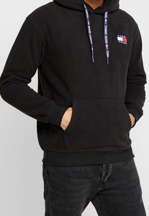 Zwarte hoodie van zachte stof, met een voorzak, verstelbare trekkoorden met logo en een klein logopatch op de borst.