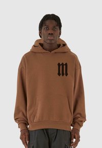 Felpa con cappuccio marrone, dotata di un grande logo "m" nero sul petto. Tessuto morbido, maniche lunghe e dettaglio con tasca frontale.