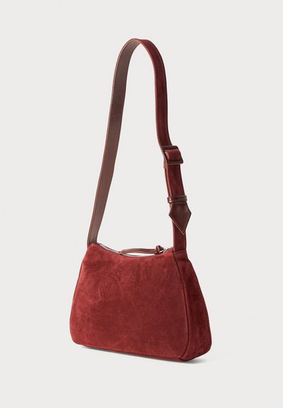 Small, deep red suede shoulder bag with adjustable strap and top zipper closure against a plain white background.