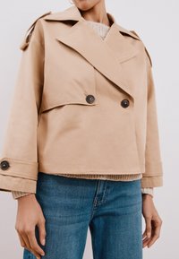 Beige, dubbelzijdig jasje met grote revers, knoopaccenten en schouderepauletten. Gemaakt van een glad materiaal met een cropped fit.