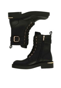 Botas de tobillo de imitación de cuero negro con cremallera lateral, parte delantera con cordones, acentos de hardware dorado y un acabado texturizado en una suela gruesa.
