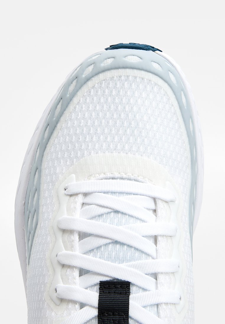 Witte sportschoen met een mesh bovenwerk, lichtblauwe accenten en een gestructureerd oppervlak. Bevat witte veters en een zwart label op de tong.