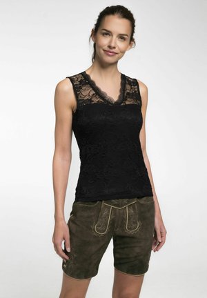 Schwarzes Spitzen-Top mit V-Ausschnitt und filigranem Blumenmuster, kombiniert mit braunen Wildledershorts, die mit detaillierten Nähten und Akzenten versehen sind.