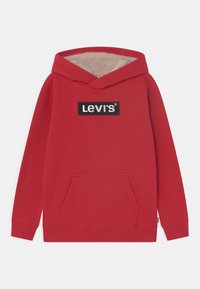 Hoodie rouge en tissu doux, avec capuche doublée crème, poche kangourou à l'avant et un patch logo rectangulaire Levis noir.
