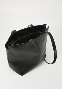 Svart lær tote bag med glidelåsåpning, to robuste håndtak, en jevn overflate og et minimalistisk design. Interiøret ser romslig ut.