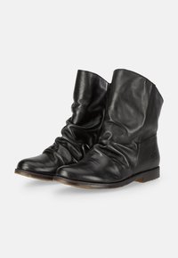 Botas de tobillo de cuero negro con un diseño arrugado, textura suave, tacón bajo y una sutil marca en el lado exterior. Forma de punta redondeada.