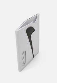 Cartera de cuero blanca con acentos de cuero negro, que presenta un diseño único, tres compartimentos para tarjetas y detalles de costura en relieve.
