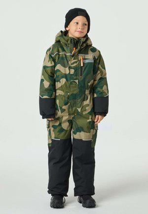 Kamouflage flyverdragt i grøn og beige med sorte bukser, hætte og reflekterende detaljer. Har lynlås foran og cargolommer.