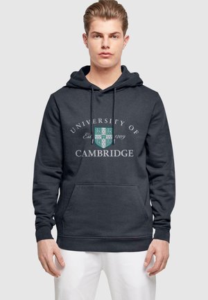 Dunkelgrauer Kapuzenpullover mit dem Aufdruck "Universität Cambridge", einem Wappenlogo, einer Fronttasche und einer verstellbaren Kapuze mit Kordelzug. Weicher Stoff.