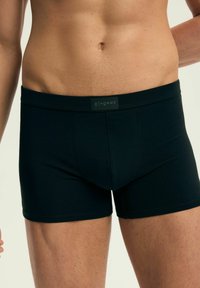 Czarne bokserki o dopasowanym kroju, wykonane z miękkiego materiału. Posiadają szeroką talię z etykietą logo na środku przodu.