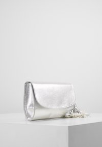 Metallic sølv clutch taske med en glat tekstur, rund form, klaplukning og hvid dusk detaljer. Velegnet til forskellige anledninger.