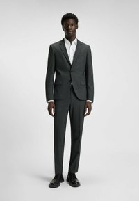 Dunkelgrauer Anzug mit tailliertem Schnitt, einreihigem Blazer, weißem Hemd und schwarzen Schnürschuhen. Hat eine glatte Oberfläche und eine strukturierte Silhouette.