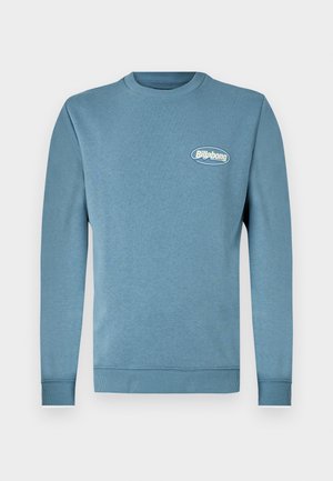 Sudadera azul claro de manga larga, cuello redondo, con puños y dobladillo acanalados. Presenta un pequeño logo blanco de "Billabong" en el pecho.