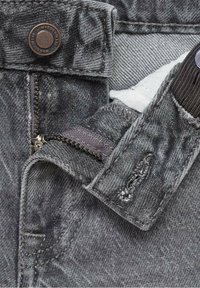 Jeans in denim grigio con zip e chiusura a bottone. Ingrandimento che mostra il tessuto testurizzato e i dettagli delle cuciture senza motivi visibili.