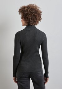 Pull à col roulé côtelé foncé en maille épaisse. Manches longues, coupe ajustée et col haut pour plus de chaleur.