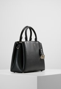 Czarna skórzana torebka o strukturalnym designie, z podwójnymi uchwytami, akcentami w złotym kolorze oraz małą metką z logo. Gładka tekstura.