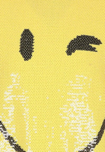 Tissu en sequins jaunes présentant un visage souriant noir avec un clin d'œil. Texture lisse avec des sequins réfléchissants créant une apparence brillante.