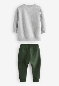 Gray sweatshirt with a round neck and long sleeves paired with green joggers featuring a side pocket and elastic waistband.