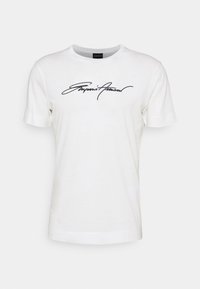 Vit bomull t-shirt med korta ärmar och rundad hals. Har en svart kursiv "Emporio Armani" logotyp på framsidan. Enfärgad design, inga mönster.