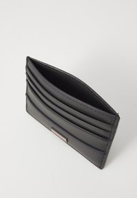 Svart lærpung med flere kortlommer og en glatt overflate. Innvendig er den foret, med en elegant sølvdetalj på forsiden.