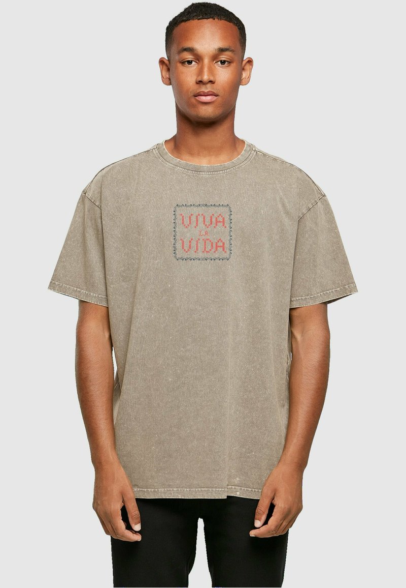 Tricou oversize bej, din bumbac, cu decolteu rotund și mâneci scurte. Prezintă brodat "VIVA LA VIDA" în roșu și albastru.