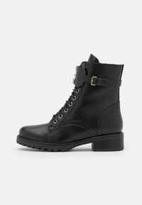 Schwarze Lederknöchelstiefelette mit runder Zehenpartie, Schnürung vorne und seitlichem Riemendetail. Verfügt über silberne Hardware und einen klobigen Absatz. Strukturierte Sohle.
