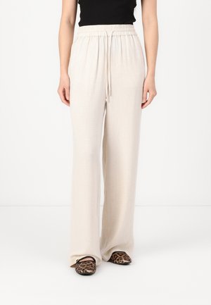 Lichtbeige wijde broek van linnen met een elastische tailleband en trekkoorddetail, gecombineerd met flats met luipaardprint.