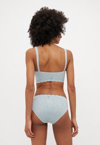 Lichtblauwe lingerie set met een kanten bralette en bijpassende hoog-gesneden slip met een golvende zoom en textuurpatroon.