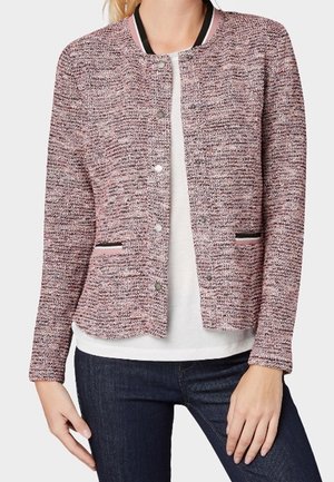 Textured pink and gray jacket with a round neckline, snap button closure, and black accents on pockets and collar. Plain white shirt underneath.
