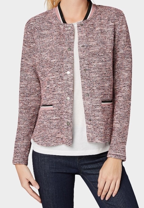 Texturierte rosa und graue Jacke mit rundem Halsausschnitt, Druckknopfverschluss und schwarzen Akzenten an Taschen und Kragen. Darunter ein schlichtes weißes Hemd.