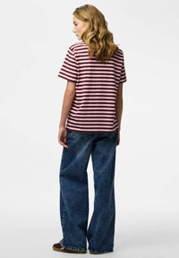 Striped shirt in burgundy and light pink, short sleeves, relaxed fit, paired with wide-leg denim jeans in a medium blue wash.