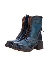 Čizme do sredine lista u tamno tirkiznoj koži s mat finišem, s smešnim akcentima, vezivanjem sprijeda, masivnim potplatima i teksturiranim dnom.