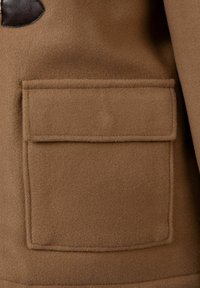 Brun uldfrakke lomme med en rektangulær klap, blød tekstur og en mørk læderdetalje i det øverste hjørne.