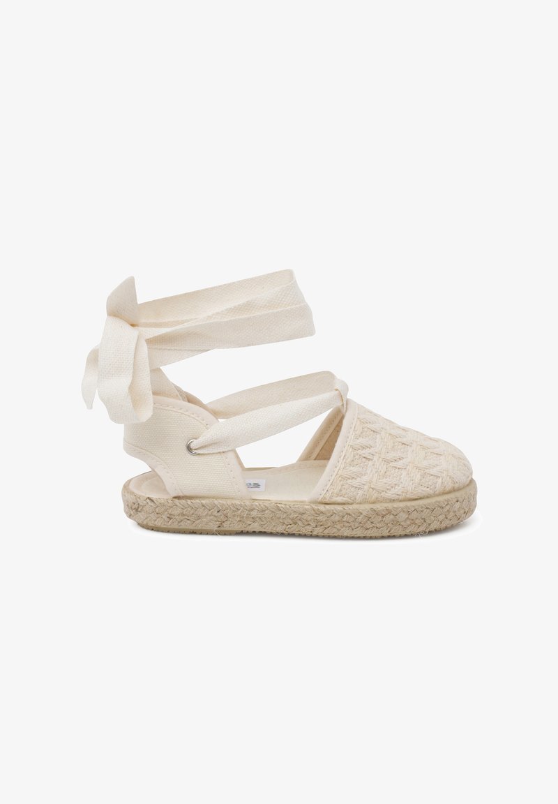 Beige kootud espadrilid kinniste rihmadega. Tekstureeritud kangast ülemine osa, jute köitest valmistatud tald ja tasane disain. Omab paela, et tagada kindel sobivus.