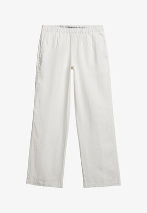 Białe lniane spodnie o luźnym kroju, z elastycznym paskiem, bokami kieszeni i teksturowanym wykończeniem materiału. Brak widocznych wzorów lub detali metalowych.