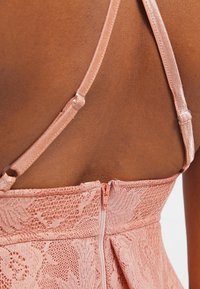 Pfirsichfarbenes Spitzenkleid mit verstellbaren Satinstreifen, einem Reißverschluss im Rücken und einem ausgestellten Saum mit kunstvollen floralen Mustern.